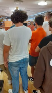 alunos de costas escutam professora na biblioteca