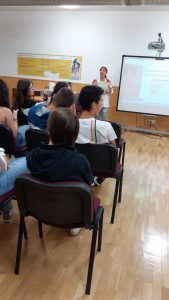 Alunos sentados escutam psicóloga